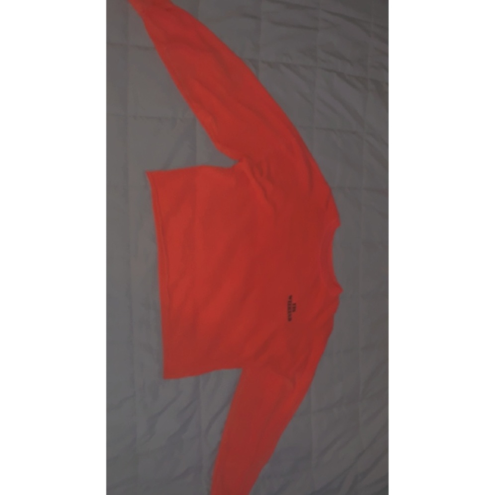 A cute orange crop top with long sleeves.